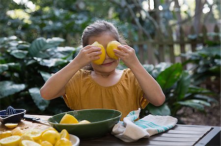 photos of gardens in florida - Girl holding lemons in front of eyes whilst preparing lemonade at garden table Stock Photo - Premium Royalty-Free, Code: 614-08946606