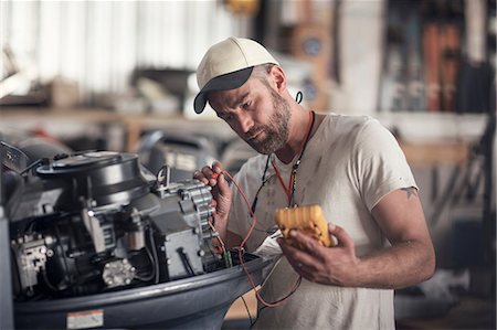 Man using machine to test outboard motor in boat repair workshop Stock Photo - Premium Royalty-Free, Code: 614-08946645