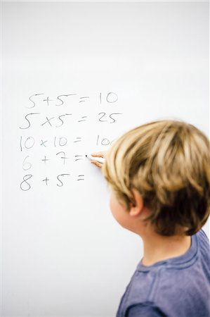 Young boy doing sums on whiteboard, rear view Stock Photo - Premium Royalty-Free, Code: 614-08984128