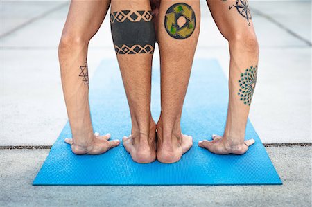 Rear view of man practicing yoga, standing on yoga mat with hands on floor Stock Photo - Premium Royalty-Free, Code: 614-08982756