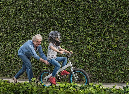 sitting in jeans - Grandmother pushing grandson on his bicycle Stock Photo - Premium Royalty-Free, Code: 614-08982826