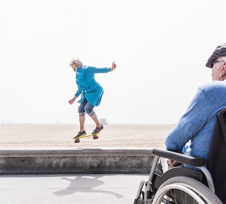 Senior man in wheelchair watching wife doing skateboard trick at beach, Santa Monica, California, USA Photographie de stock - Premium Libres de Droits, Code: 614-08982917