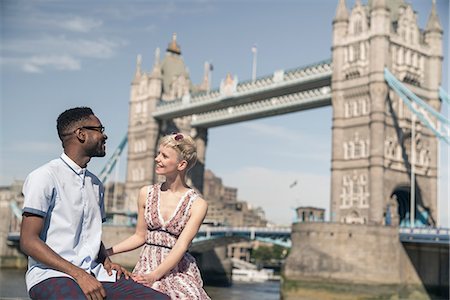 simsearch:614-06896801,k - Young couple sitting on wall, smiling, Tower Bridge in background, London, England, UK Stock Photo - Premium Royalty-Free, Code: 614-08983256
