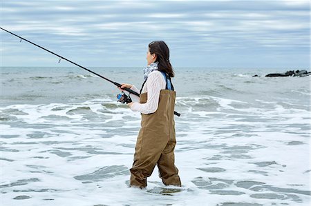 sports and fishing - Young woman in waders sea fishing knee deep in water Stock Photo - Premium Royalty-Free, Code: 614-08990755