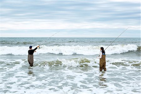 Young couple in waders, casting off sea fishing rods in sea Stock Photo - Premium Royalty-Free, Code: 614-08990764