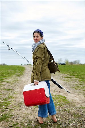 Young female sea fisher looking back on dirt track Stock Photo - Premium Royalty-Free, Code: 614-08990784