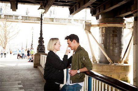 simsearch:614-06896801,k - Young couple, standing underneath bridge, young woman touching man's face, smiling Stock Photo - Premium Royalty-Free, Code: 614-08990825