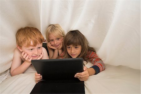 den - Children lying in bed looking at digital tablet Stock Photo - Premium Royalty-Free, Code: 614-08991156