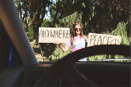 Car window view of young female boho hitchhiker with peace sign Stock Photo - Premium Royalty-Free, Code: 614-08991240