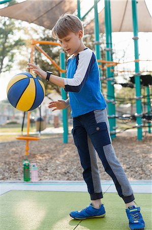 Boy bouncing basketball in playground Stock Photo - Premium Royalty-Free, Code: 614-09017367