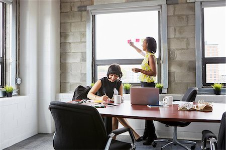 simsearch:614-08030536,k - Two women working in meeting room, young woman sticking sticky notes to window Stock Photo - Premium Royalty-Free, Code: 614-09017708
