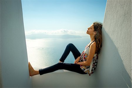 portrait girl profile - Girl sitting, leaning against wall, sea in background, O'a, Santorini, Kikladhes, Greece Stock Photo - Premium Royalty-Free, Code: 614-09017803