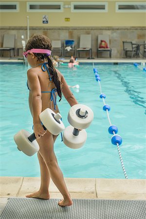 swimwear indoors - Girl carrying dumbbell-shaped floats by poolside Stock Photo - Premium Royalty-Free, Code: 614-09017865