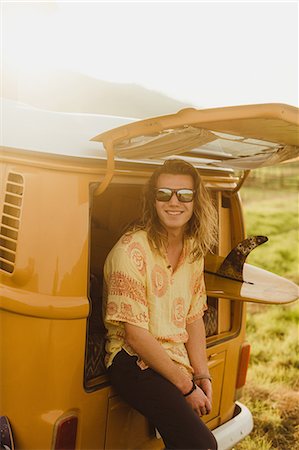 Portrait of young male surfer with long hair leaning against vintage recreational vehicle, Exeter, California, USA Stock Photo - Premium Royalty-Free, Code: 614-09026452