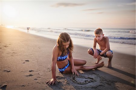 Girl drawing heart in sand on beach Stock Photo - Premium Royalty-Free, Code: 614-09026967