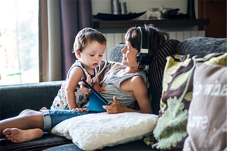 Curious male toddler looking at brother's digital tablet on sofa Photographie de stock - Premium Libres de Droits, Code: 614-09038547