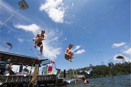 Teenagers jumping into lake, low angle view Stock Photo - Premium Royalty-Free, Code: 614-09038581