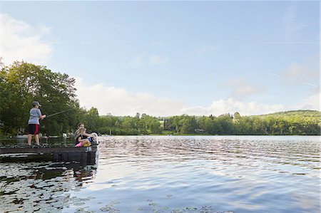 Three children on jetty beside lake, young boy fishing using fishing rod Stock Photo - Premium Royalty-Free, Code: 614-09038775