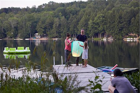 releasing - Father and daughters standing on jetty, releasing sky lantern, woman photographing event using smartphone Stock Photo - Premium Royalty-Free, Code: 614-09038790