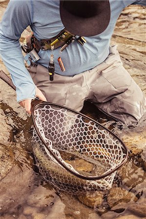 Fisherman kneeling with caught netted fish in river, Mozirje, Brezovica, Slovenia Stock Photo - Premium Royalty-Free, Code: 614-09057009