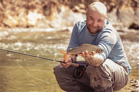 slovenia - Fisherman holding caught fish in river, Mozirje, Brezovica, Slovenia Stock Photo - Premium Royalty-Free, Code: 614-09057001