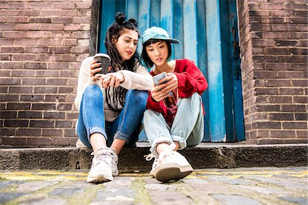 europe sidewalk cafe - Two young women sitting on sidewalk looking at smartphone Photographie de stock - Premium Libres de Droits, Code: 614-09057130