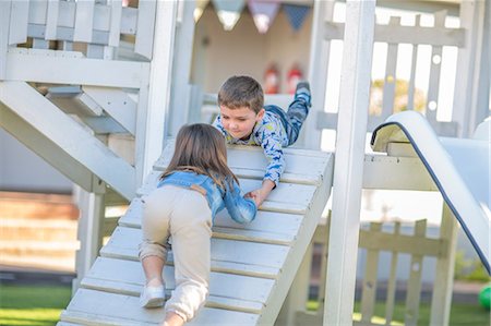 Girl and boy at preschool, helping hand to crawl up ramp on climbing frame in garden Stock Photo - Premium Royalty-Free, Code: 614-09057255