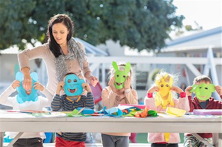 Mid adult woman helping children with crafting activity, children wearing paper masks Photographie de stock - Premium Libres de Droits, Code: 614-09057326