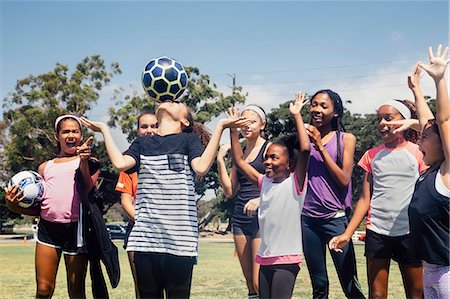 simsearch:614-08270379,k - Schoolgirl soccer team watching player balancing soccer ball on nose on school sports field Stock Photo - Premium Royalty-Free, Code: 614-09078961