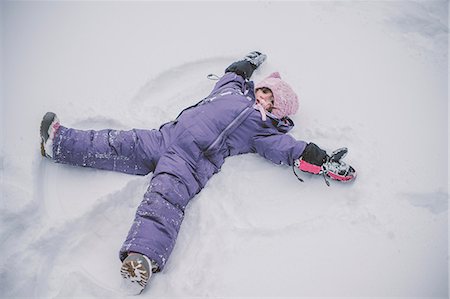 Young girl making snow angel in snow Stock Photo - Premium Royalty-Free, Code: 614-09110804