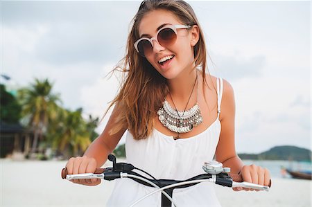 Portrait of young woman holding bicycle handlebars on sandy beach, Krabi, Thailand Stock Photo - Premium Royalty-Free, Code: 614-09111005