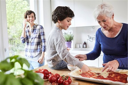 simsearch:649-07761247,k - Grandmother and grandson making pizza in kitchen, mother in background using smartphone Stock Photo - Premium Royalty-Free, Code: 614-09127329