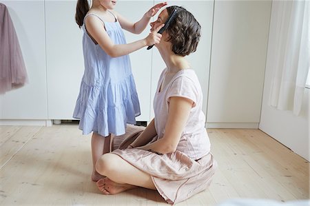 Mother sitting on floor, daughter brushing mother's hair, mid section Stock Photo - Premium Royalty-Free, Code: 614-09127358