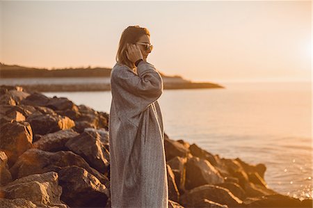 simsearch:614-08392638,k - Portrait of woman wearing sunglasses and winter coat standing on rocks looking away at sea, Odessa, Odeska Oblast, Ukraine, Eastern Europe Stock Photo - Premium Royalty-Free, Code: 614-09147681