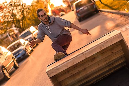 ramps on the road - Young male skateboarder turning moving up ramp on suburban street at sunset Foto de stock - Sin royalties Premium, Código: 614-09159595