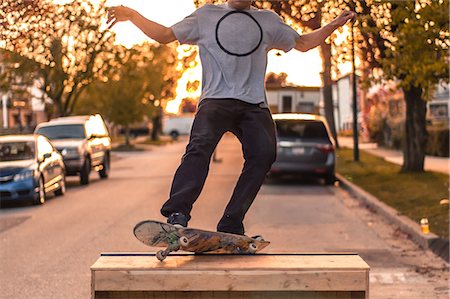 ramps on the road - Young male skateboarder balancing on top of ramp on suburban street at sunset, neck down Foto de stock - Sin royalties Premium, Código: 614-09159593