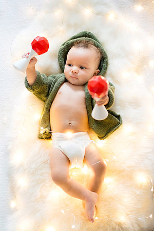 simsearch:614-07031850,k - Baby boy lying on furry rug amongst decorative lights playing with rattles Stock Photo - Premium Royalty-Free, Code: 614-09183050