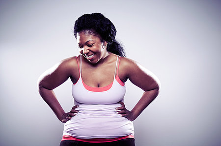 fat african american excercise - Mid adult woman wearing white vest, hands on hips Stock Photo - Premium Royalty-Free, Code: 614-09209927