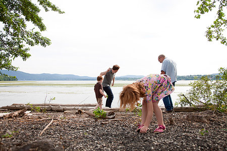 Girl and family throwing stones into river Stock Photo - Premium Royalty-Free, Code: 614-09210066