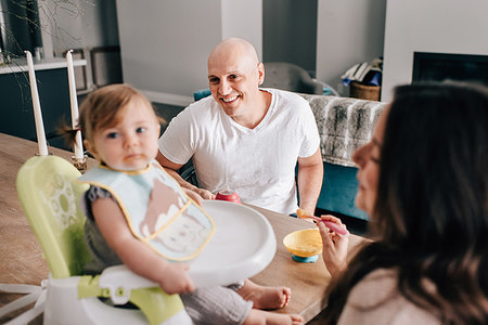 simsearch:614-06896477,k - Mother and father feeding baby daughter in child seat on kitchen table Stock Photo - Premium Royalty-Free, Code: 614-09258595