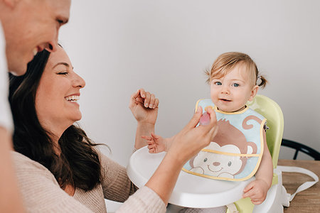 simsearch:614-06896477,k - Mother and father feeding baby daughter in child seat, portrait Stock Photo - Premium Royalty-Free, Code: 614-09258597