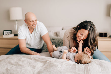 simsearch:614-06896477,k - Mother and father on bed playing with baby daughter Stock Photo - Premium Royalty-Free, Code: 614-09258615