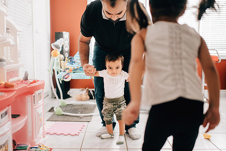 Girl in front of father walking baby brother in kitchen Stock Photo - Premium Royalty-Free, Code: 614-09253669