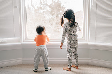 Girl and baby brother looking through living room window, rear view Stock Photo - Premium Royalty-Free, Code: 614-09253704