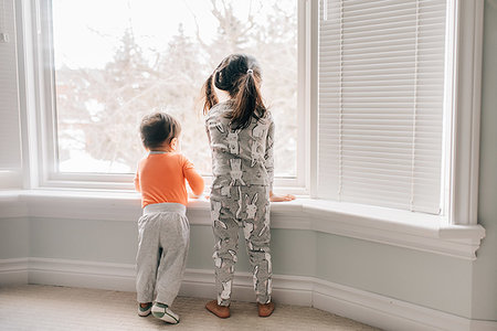 Girl and baby brother looking through living room window, rear view Stock Photo - Premium Royalty-Free, Code: 614-09253703