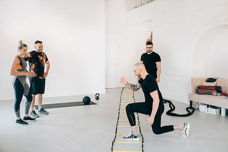 female wearing trainers - Couple observing fitness instructor using agility ladder in studio Stock Photo - Premium Royalty-Free, Code: 614-09276248