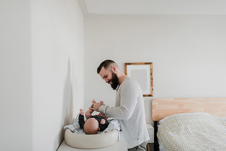 Young man changing baby son's diaper in bedroom Stock Photo - Premium Royalty-Free, Code: 614-09276685