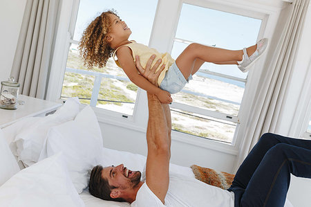 simsearch:614-08030822,k - Father lifting daughter in mid air on bed in beach house Stock Photo - Premium Royalty-Free, Code: 614-09276861