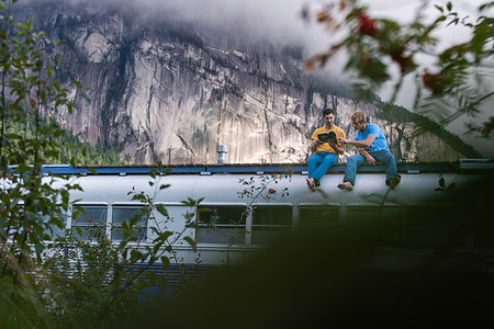 Friends reading book on roof of motorhome, Squamish, British Columbia, Canada Stock Photo - Premium Royalty-Free, Code: 614-09277018