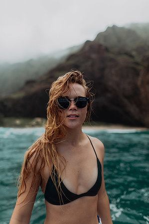 Woman in sunglasses and bikini by seaside, mountains in background, Princeville, Hawaii, US Stock Photo - Premium Royalty-Free, Code: 614-09270228